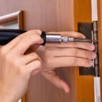A-person-is-using-a-screwdriver-to-tighten-a-screw-for-a-door-installation